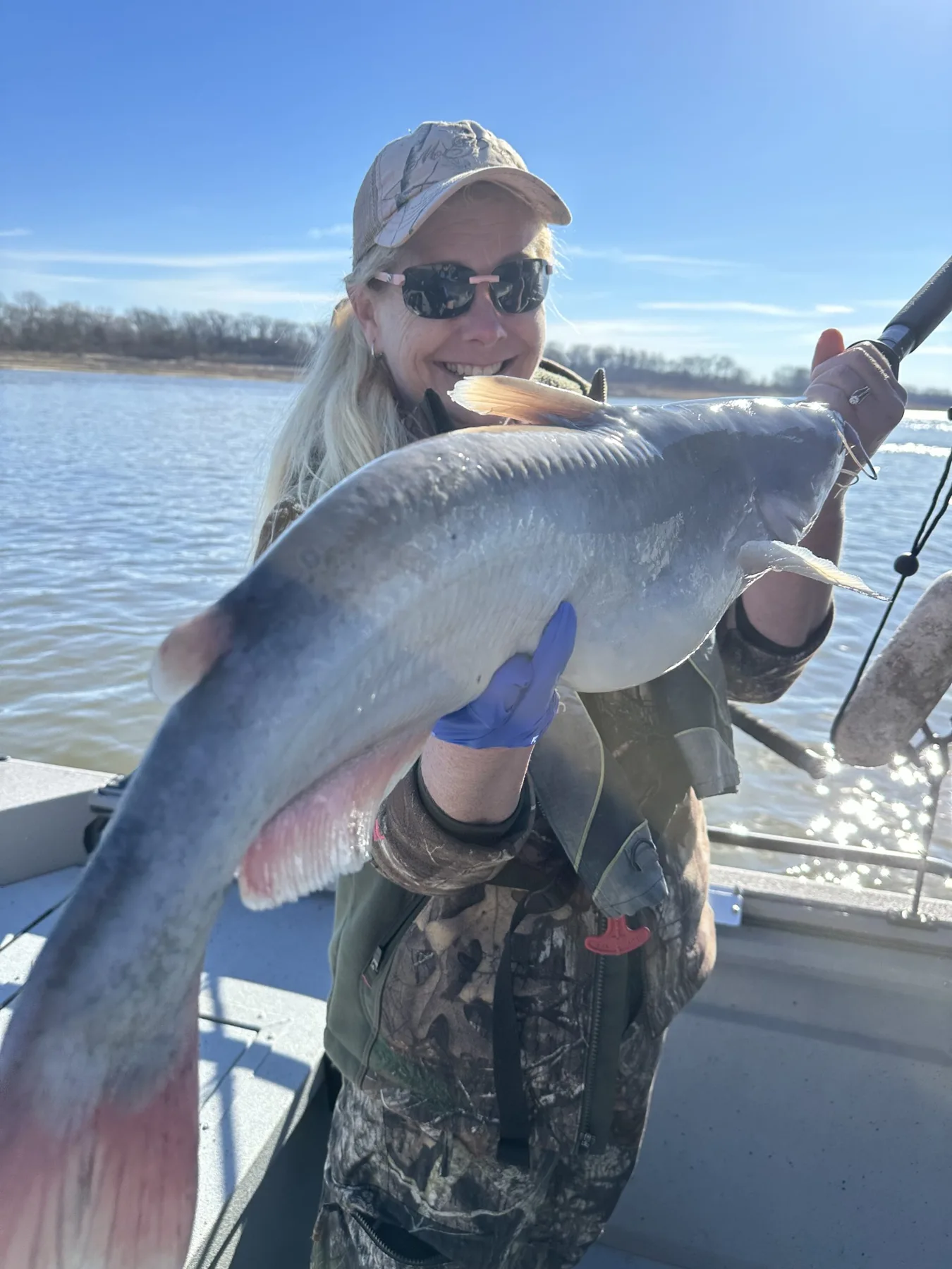 An angler with a large catfish on a cold river day