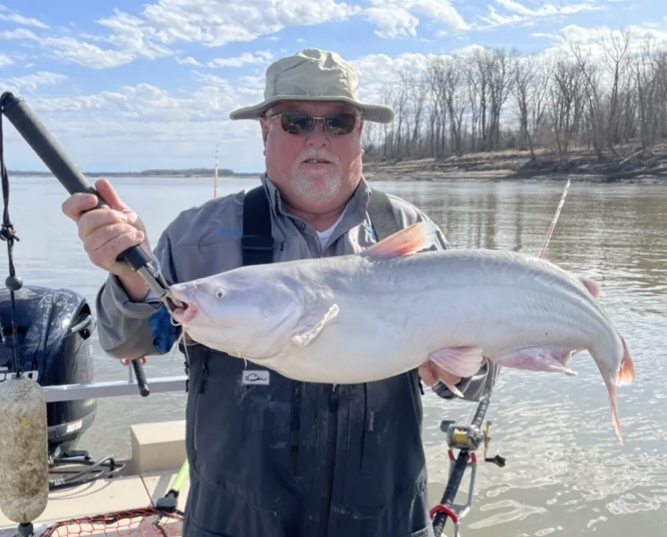 Captain Dave holding a catfish beside the river