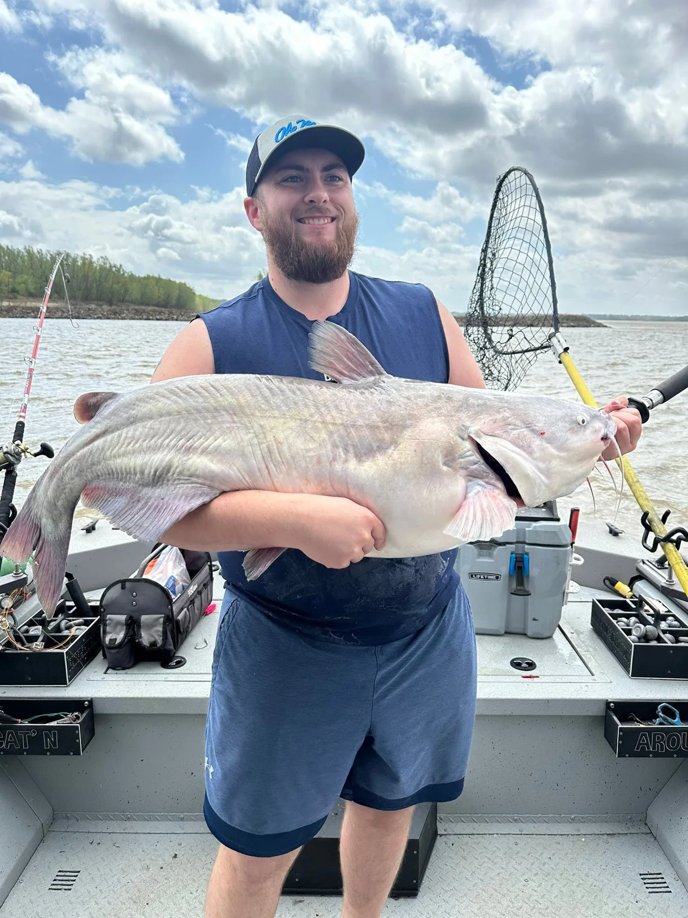 A smiling angler holding a large catfish on the boat