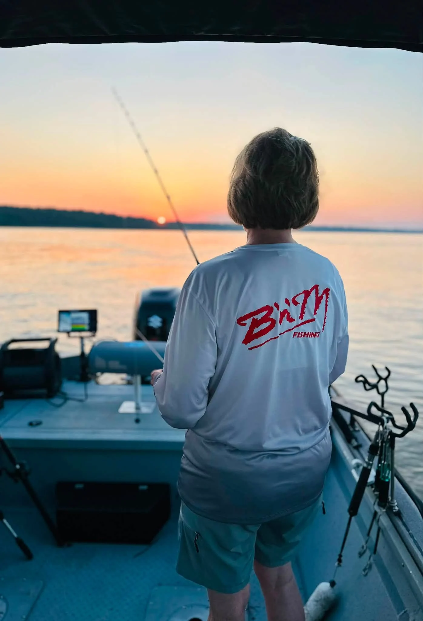 An angler fishing from the deck in warm sunrise light